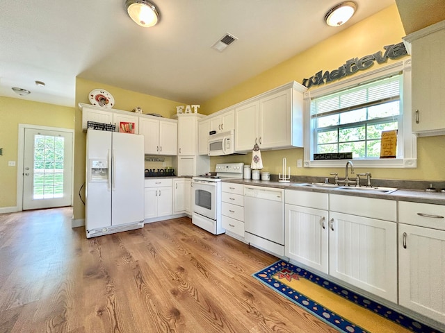 kitchen with white appliances, white cabinetry, light hardwood / wood-style floors, and sink