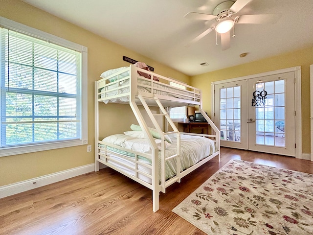 bedroom featuring multiple windows, hardwood / wood-style floors, ceiling fan, and french doors