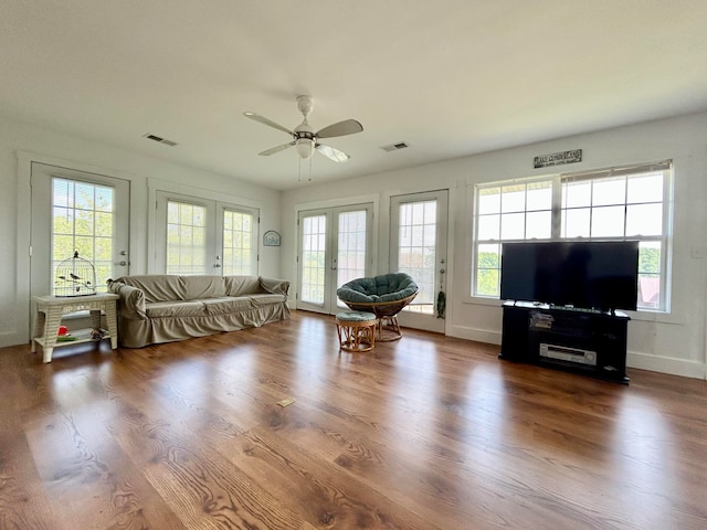 living room featuring ceiling fan, dark wood-type flooring, and plenty of natural light