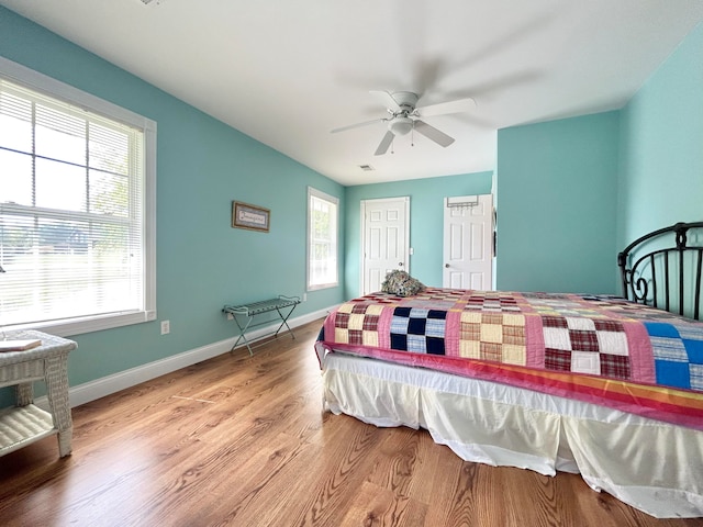 bedroom featuring ceiling fan, multiple windows, and light wood-type flooring