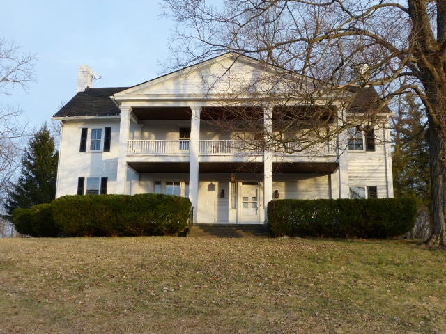 neoclassical / greek revival house with a front lawn and a balcony