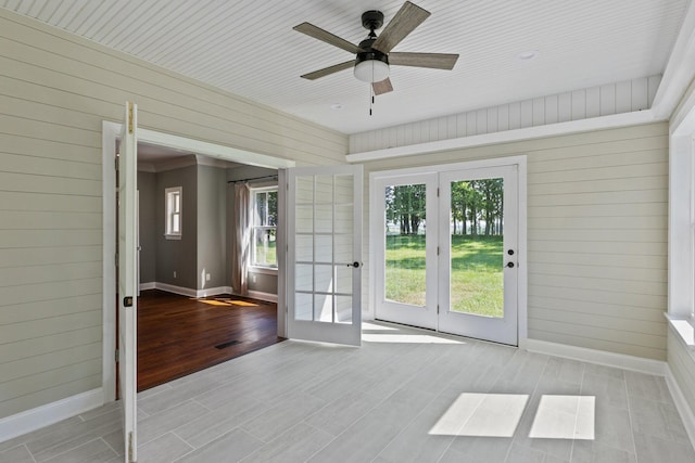 interior space featuring visible vents, baseboards, wood walls, wood finished floors, and a ceiling fan