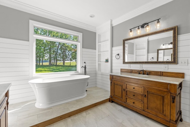 full bathroom featuring wood walls, ornamental molding, wainscoting, a freestanding tub, and vanity