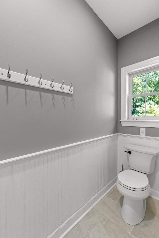 bathroom featuring tile patterned flooring, toilet, and wainscoting