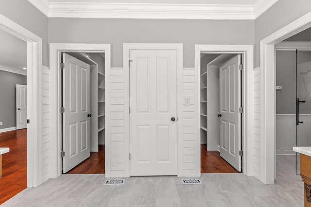 bedroom featuring a walk in closet, visible vents, ornamental molding, wood finished floors, and a closet