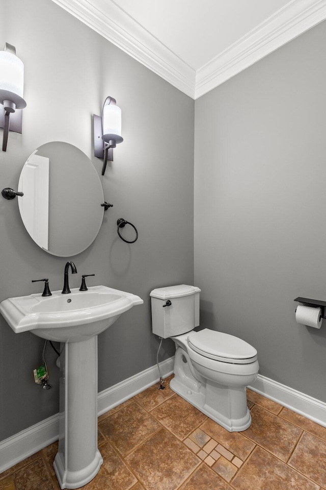 half bathroom with a sink, toilet, baseboards, and ornamental molding