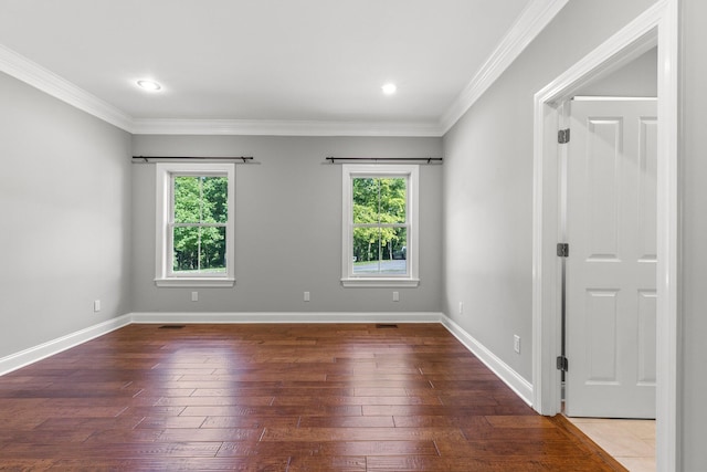 empty room featuring plenty of natural light, crown molding, and hardwood / wood-style flooring