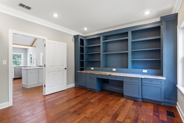 unfurnished office featuring dark wood finished floors, visible vents, built in desk, and ornamental molding