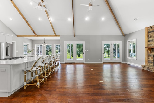 living room with dark wood-type flooring, baseboards, beam ceiling, ceiling fan with notable chandelier, and a fireplace