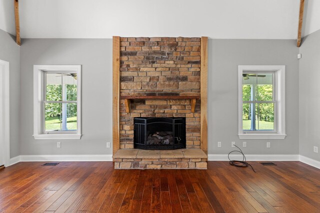 unfurnished living room with beamed ceiling, a healthy amount of sunlight, and a brick fireplace