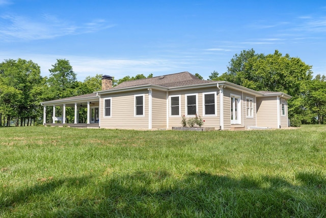 back of property featuring a lawn, a chimney, and ceiling fan