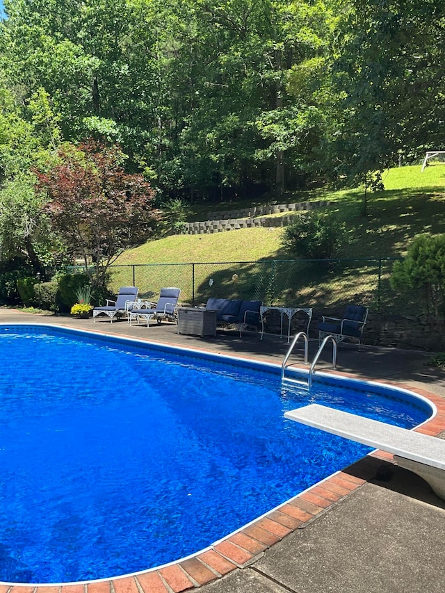 view of swimming pool featuring an outdoor hangout area, a patio, and a diving board