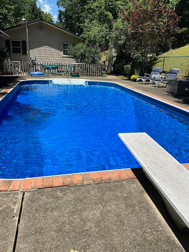 view of swimming pool featuring a patio and a diving board