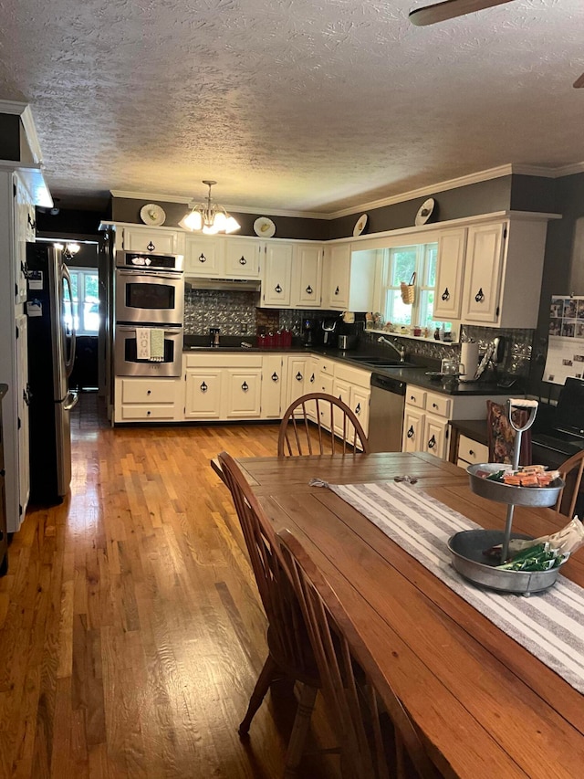 dining room featuring a notable chandelier, plenty of natural light, light hardwood / wood-style floors, and a textured ceiling