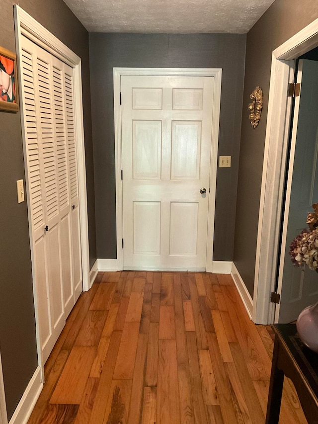 hallway featuring a textured ceiling and light hardwood / wood-style flooring