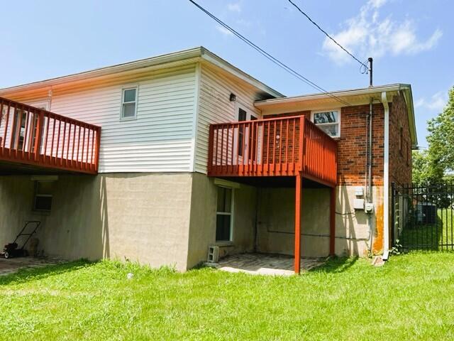 back of house featuring a wooden deck and a lawn