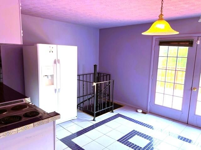 kitchen featuring light tile floors, decorative light fixtures, a textured ceiling, french doors, and white refrigerator with ice dispenser