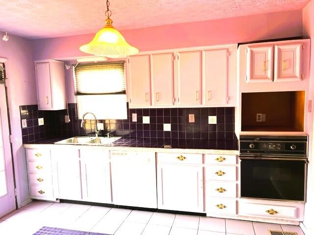 kitchen with black oven, sink, a healthy amount of sunlight, and tile counters