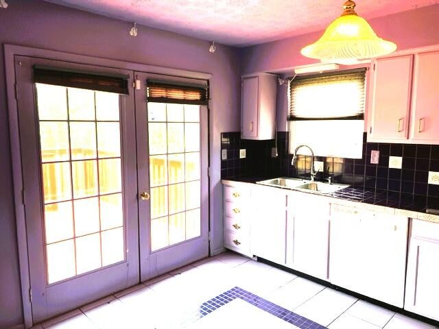 kitchen with a healthy amount of sunlight, light tile floors, and white cabinets