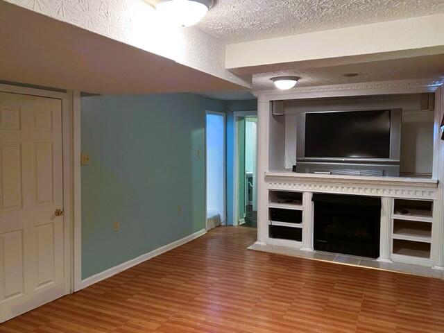 unfurnished living room featuring a textured ceiling and hardwood / wood-style flooring