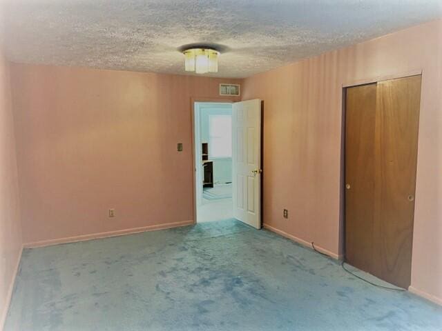 unfurnished bedroom featuring light colored carpet, a closet, and a textured ceiling