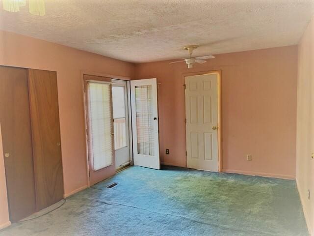 unfurnished room with ceiling fan, a textured ceiling, and light carpet