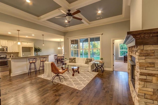 interior space featuring coffered ceiling, a fireplace, ceiling fan with notable chandelier, and dark wood-type flooring