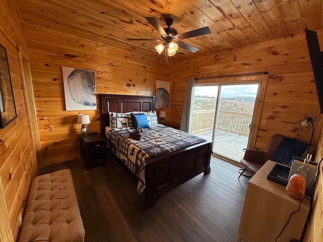 bedroom featuring ceiling fan, wood walls, access to exterior, and dark wood-type flooring