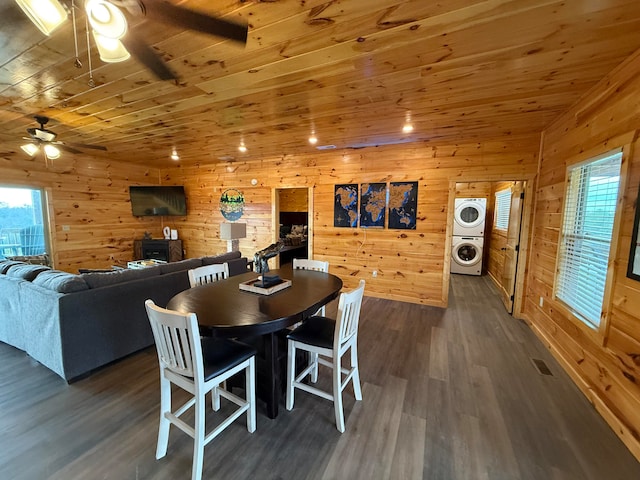 dining room featuring stacked washer / dryer, wooden ceiling, dark wood-type flooring, and wood walls