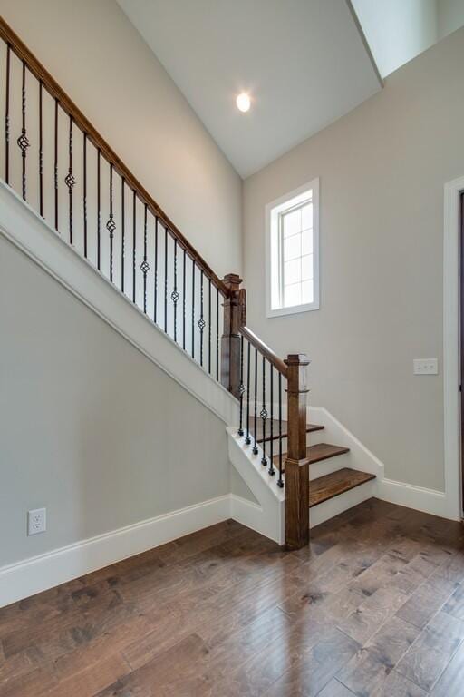 staircase with dark hardwood / wood-style flooring and lofted ceiling