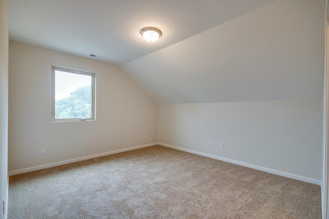 additional living space with light colored carpet and vaulted ceiling