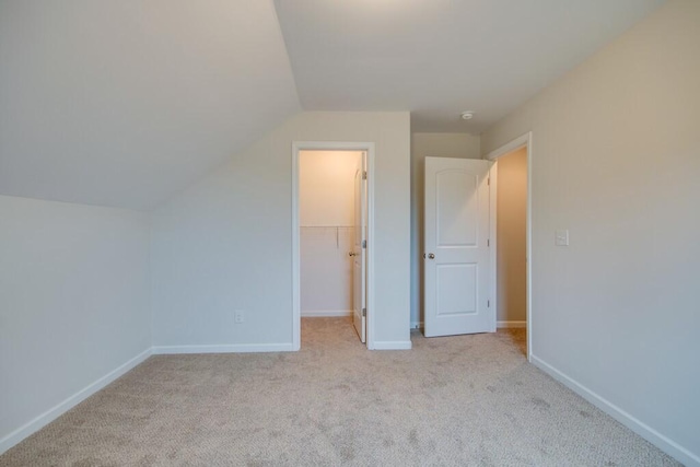 additional living space featuring light colored carpet and vaulted ceiling