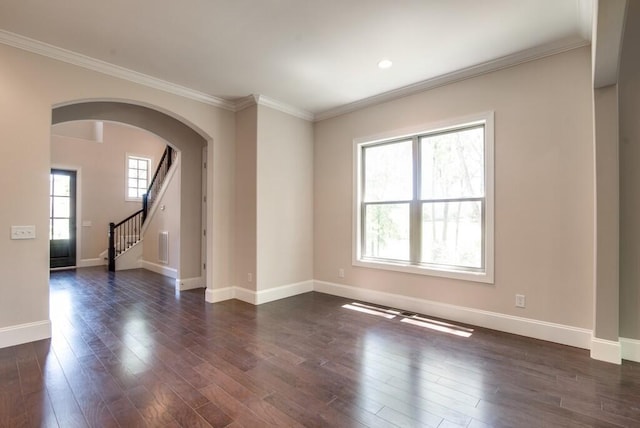 spare room featuring crown molding, plenty of natural light, and dark wood-type flooring