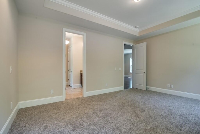 unfurnished bedroom featuring light colored carpet, ornamental molding, and a tray ceiling