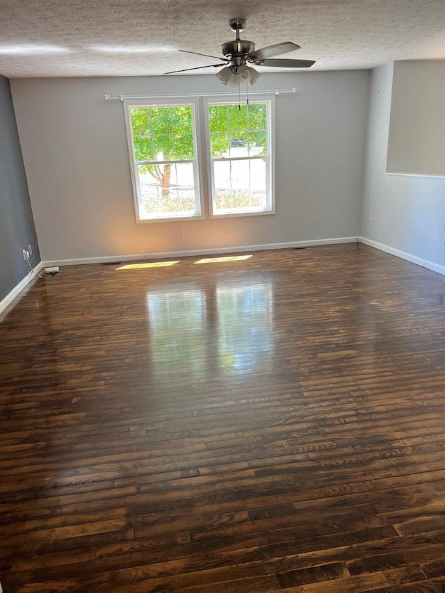 unfurnished room with a textured ceiling, dark wood-style flooring, and baseboards