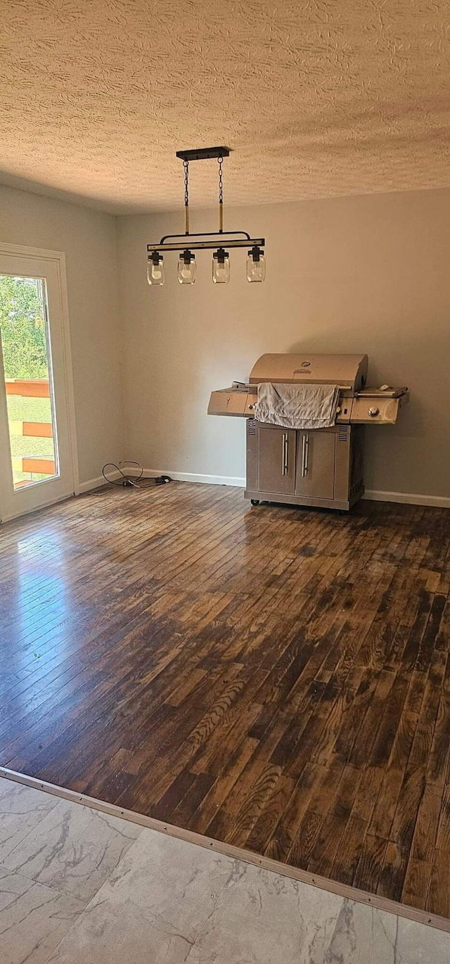 empty room featuring dark wood-style floors, a textured ceiling, and baseboards