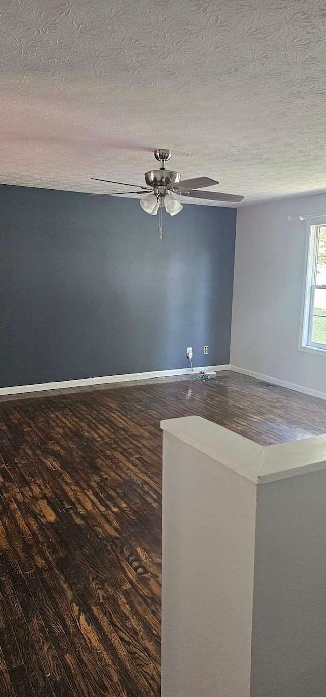 unfurnished room with ceiling fan, a textured ceiling, baseboards, and wood finished floors