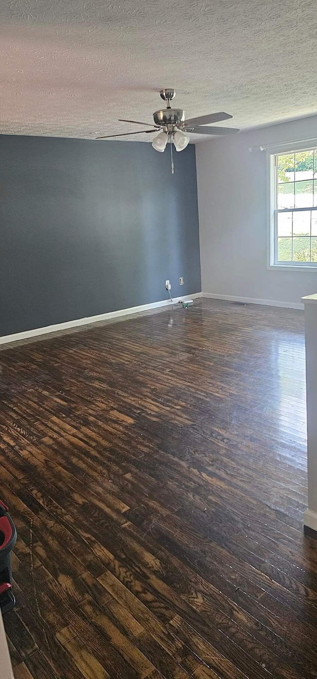 unfurnished room featuring dark wood-style floors, ceiling fan, a textured ceiling, and baseboards