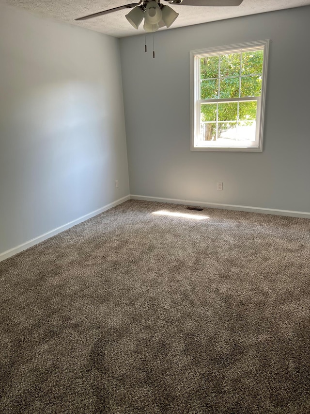 empty room featuring a textured ceiling, ceiling fan, carpet flooring, and baseboards