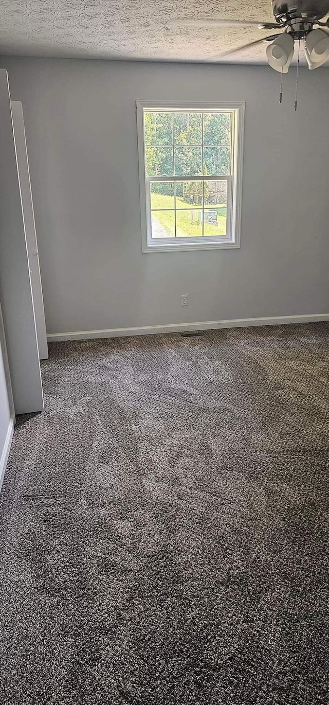 empty room with baseboards, a textured ceiling, and carpet flooring