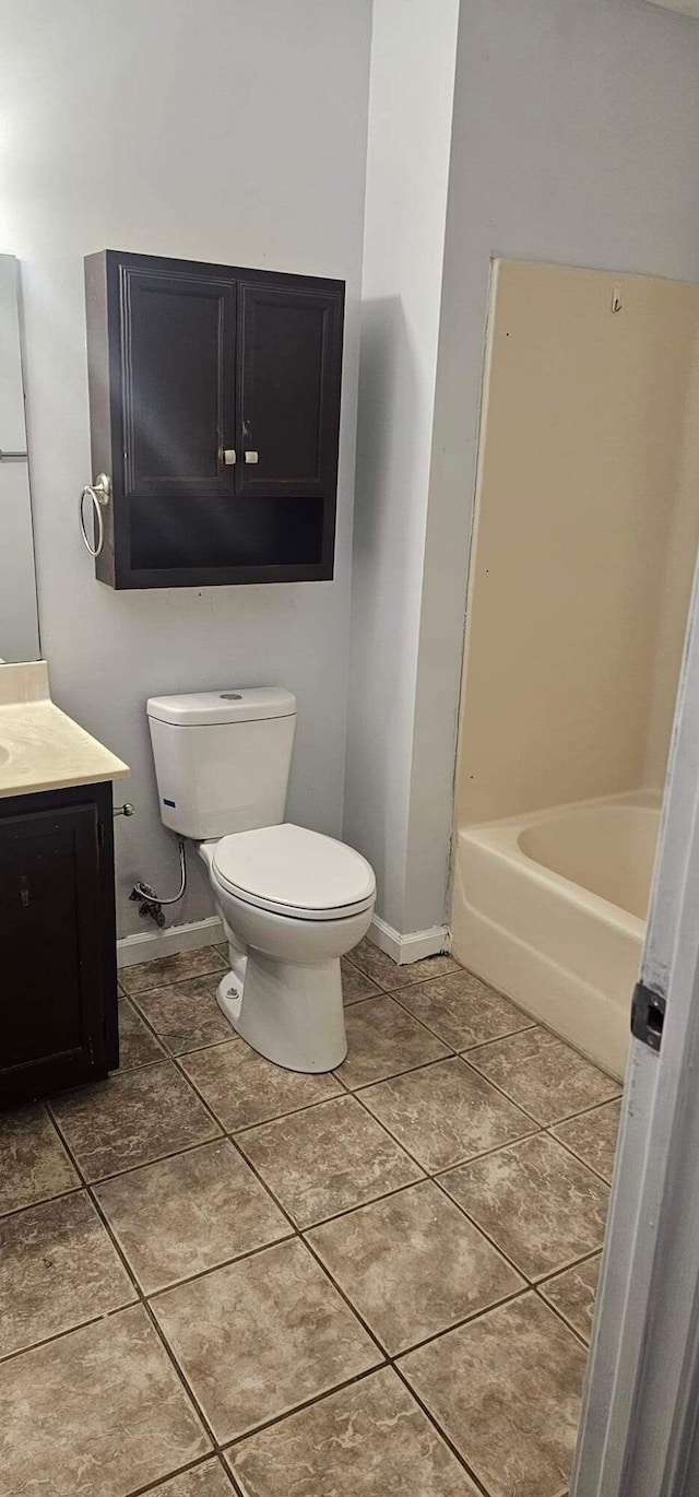 bathroom with a bathtub, toilet, vanity, baseboards, and tile patterned floors