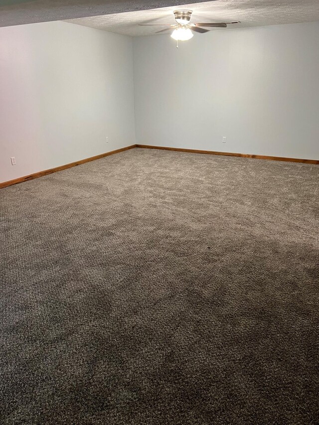 carpeted empty room featuring ceiling fan, baseboards, and a textured ceiling