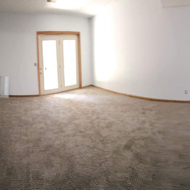 carpeted spare room featuring radiator and baseboards