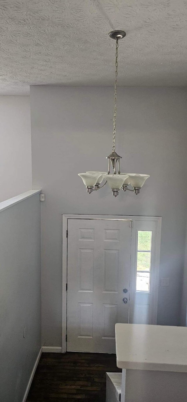 foyer entrance featuring dark wood-style floors, a textured ceiling, and baseboards