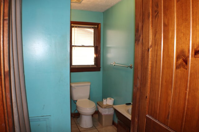 bathroom featuring tile floors, toilet, and a textured ceiling