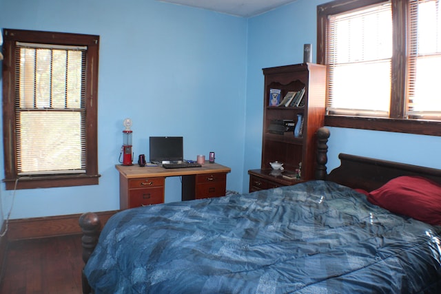 bedroom with multiple windows and dark hardwood / wood-style floors