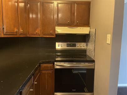 kitchen with stainless steel range with electric stovetop, dark stone counters, and tasteful backsplash