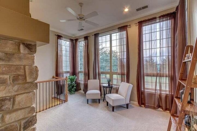 sitting room featuring ceiling fan, carpet flooring, crown molding, and a wealth of natural light