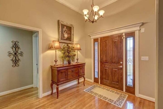 foyer entrance with hardwood / wood-style flooring, an inviting chandelier, and ornamental molding