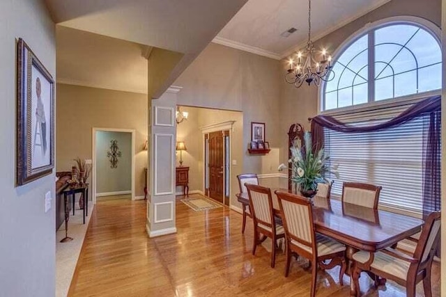 dining space with light hardwood / wood-style floors, crown molding, and a notable chandelier